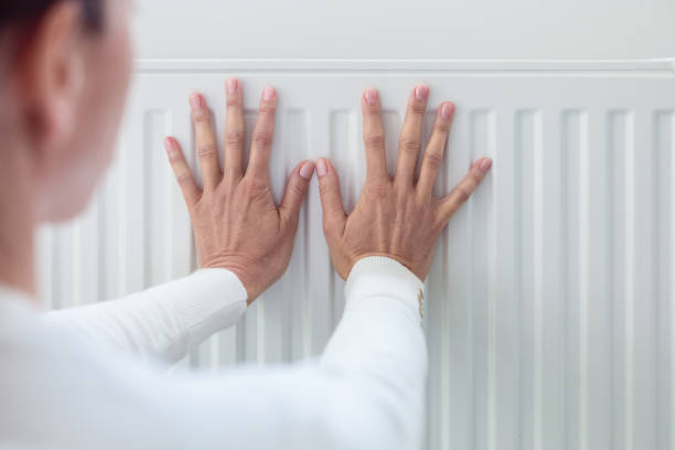 istock Woman warms up hands over heater 1542458876