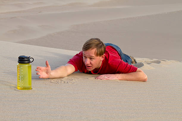 atteindre pour une bouteille d'eau - thirsty desert men reaching photos et images de collection