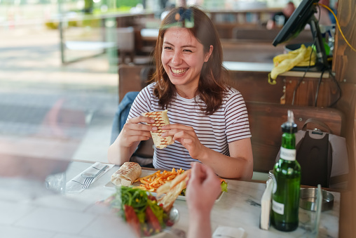 Young woman eating wrap sandwich in restaurant