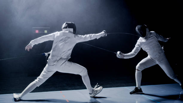 istock Two professional fencers foil swords dueling each other in combat with epic blue stage lighting and smoke effects. Parrying 1542472236