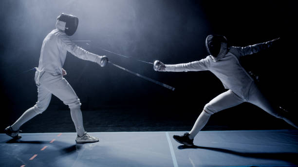 istock Two professional fencers foil swords dueling each other in combat with epic blue stage lighting and smoke effects 1542472238
