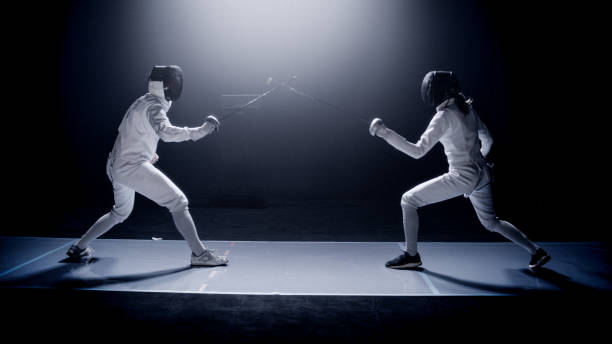 istock Two professional fencers foil swords facing each other in combat with epic blue stage lighting and smoke effects 1542472266