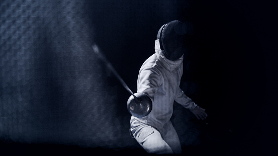 FPV two fencers dueling in a fencing sports match on lit-up stage. Foil swords clashing to determine the match winner