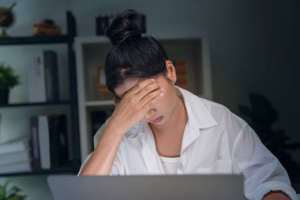 istock Asian business woman have a headache because using the computer and working for a long time at night. 1542477006