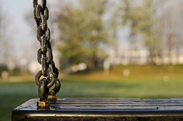 Icy chain of a seesaw in the local park (Italy, Crema, Bonaldi), with defocused background.