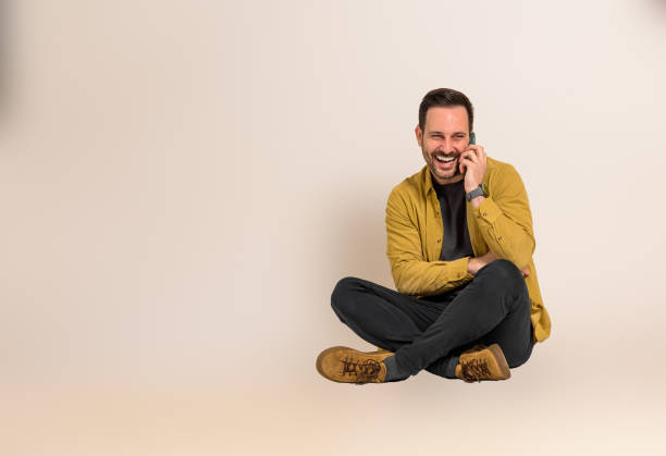 istock Cheerful male freelancer discussing project strategies with client over mobile phone while sitting against background. Young businessman laughing and communicating over cellphone 1542497420