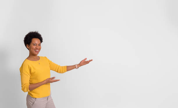 istock Smiling female promoter presenting new product on copy space while standing over white background 1542498061