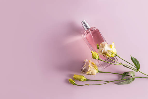 istock An elegant bottle of eau de parfum or cosmetic spray on a pastel background with spring austoma flowers. Top view. space for text. 1542498694