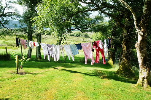 White clothes hanging backlit outdoors with sunny landscape background. Horizontal composition.