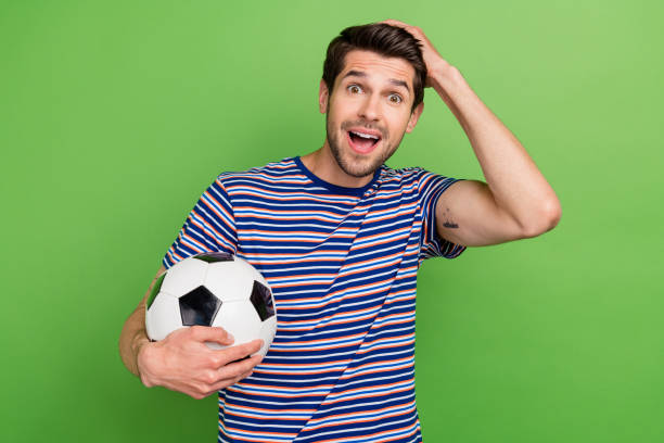 photo of young sporty guy holding ball soccer fan support barcelona club losers champions leagues isolated on green color background - fútbol club barcelona 個照片及圖片檔