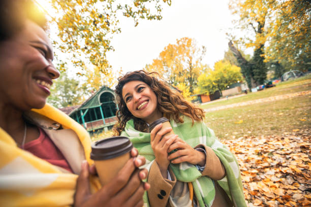 istock Two smiling young women friends chatting outdoors and drinking coffee while enjoying the walk in the park together 1542528549