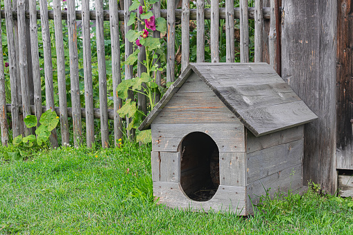 old wooden doghouse, with wooden fence in the background