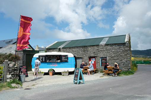 Allihies, Ireland - June 20th, 2023: Tourists enjoying snacks and refreshments from a mobile pop-up barista style caravan, near the beach at Allihies, County Cork, Ireland.  Allihies is on the popular tourist route named the Wild Atlantic Way on the west coast.