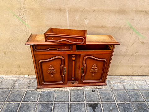 High angle view of wooden vintage ornate cabinet left in the street in the city of Valencia, Spain