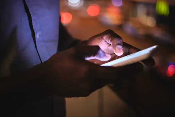 Photo of Phone, night and hands with a business man on a balcony in the city for communication or networking. Mobile, social media or contact with a male employee standing outside of his office in the evening