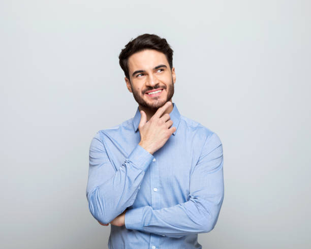istock Confident young businessman with hand on chin 1542565490