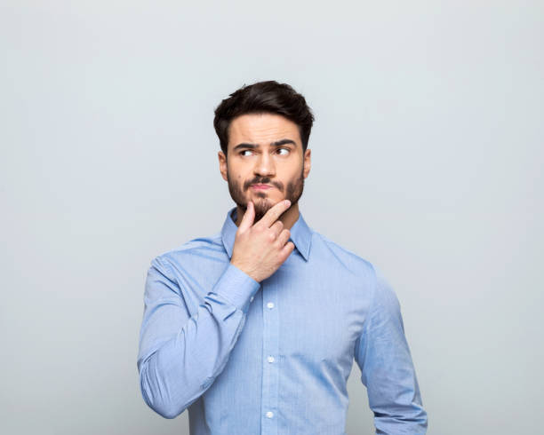 istock Thoughful businessman standing with hand on chin 1542565933