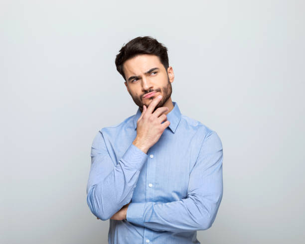 istock Thoughful businessman standing with hand on chin 1542565981