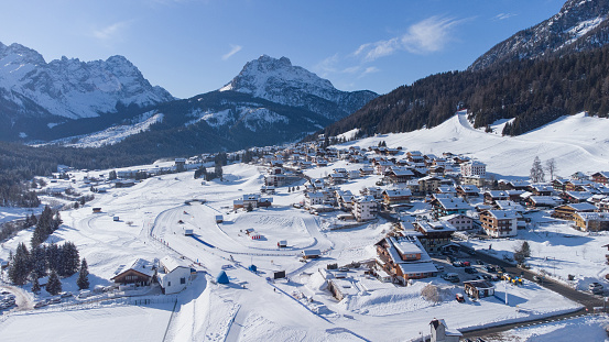 Aerial drone panorama of village of Sappada in italian Dolomites on a sunny winter day packed with snow. Beautiful alpine village in Dolomites.