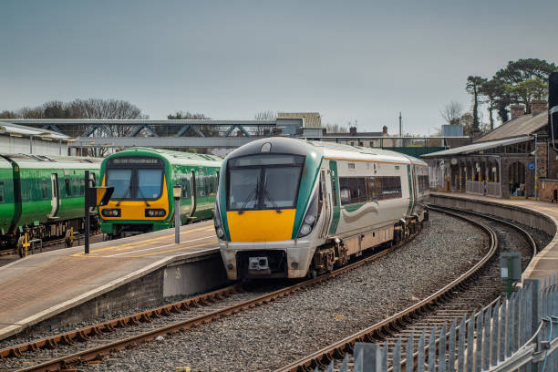 Trains on Drogheda macbride train station in ireland, on a line from Dublin to Belfast. Rail platforms and trains passing by on a sunny day.