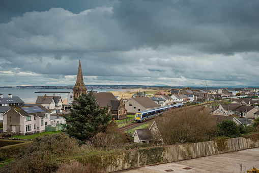 Train driving through the city of Castlerock in Northern Ireland on a cloudy spring day. Commuting through beautiful irish countryside and villages.