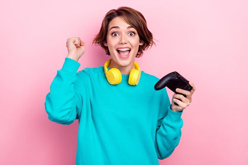 Portrait of delighted positive lady hold controller raise fist luck triumph video game isolated on pink color background.