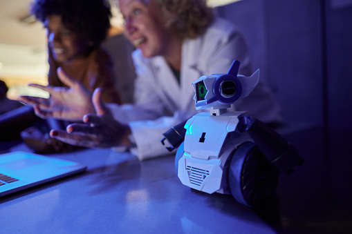 Close up of futuristic robot with a teacher and schoolkid in laboratory.