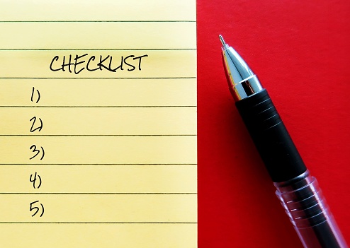 Pen writing on a note CHECKLIST, means list of all things need to do or information to find out or things need to take somewhere