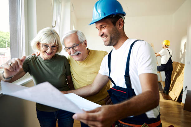 istock Happy senior couple analyzing housing plans with manual worker. 1542599477