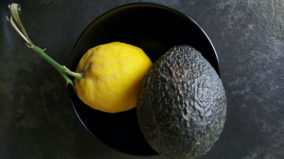 lemon and avocado in a black bowl