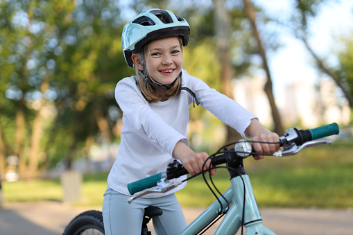 Portrait of a little girl in a helmet who enjoys a bike ride.