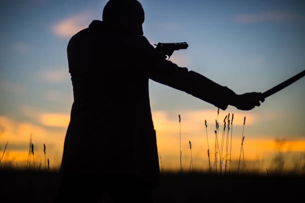 istock Silhouette of a demon and vampire hunter with a dramatic sky in the background. A man with a katana and a revolver. Fantasy and halloween concept 1542635121