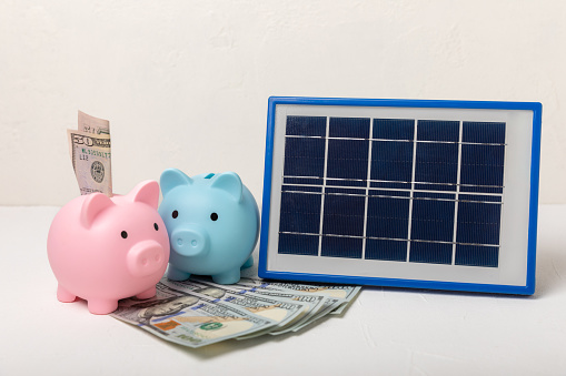 Flat lay composition with solar panel, led lamp and piggy bank on  background. The concept of saving money and clean energy. The concept of ecology and sustainable development.