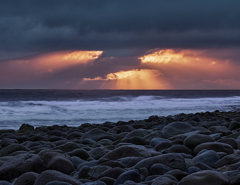 Rocky beach and Norwegian sea at sunset.