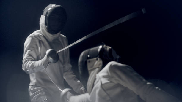 istock Two professional fencers foil swords clashing in combat. Ducking and dodging 1542653092