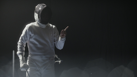 Studio shot of a fencer showing off the equipment and challenging the camera