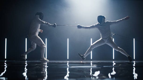 istock Two professional fencers foil swords dueling each other in combat with epic blue stage lighting 1542655844