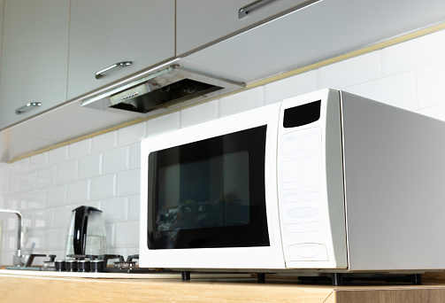istock Modern white microwave on the kitchen countertop.Using microwave everyday in the kitchen. The concept of cooking. 1542660682