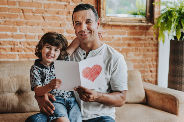 istock Son handing postcard to father on father's day looking at camera 1542664985