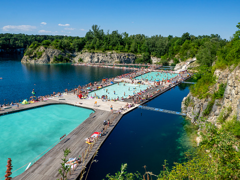 Krakow, Poland - July 8, 2023: Swimming and paddling pools on a Zakrzowek lake with steep cliffs in place of former flooded limestone quarry. Newly opened recreational place with a crowd of people