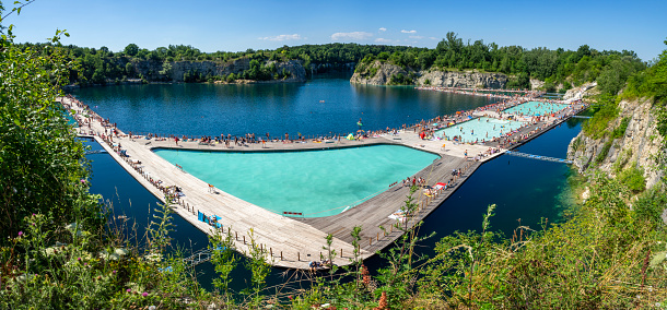 Krakow, Poland - July 8, 2023: Swimming and paddling pools on a Zakrzowek lake with steep cliffs in place of former flooded limestone quarry. Newly opened recreational place with a crowd of people