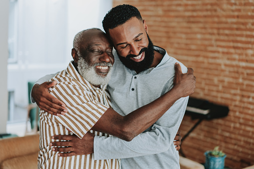 Adult son hugging senior father at home