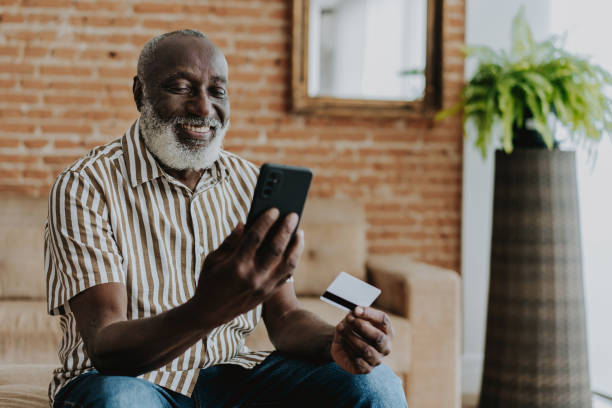 portrait of senior man shopping by smartphone with credit card - shopping e commerce internet credit card imagens e fotografias de stock