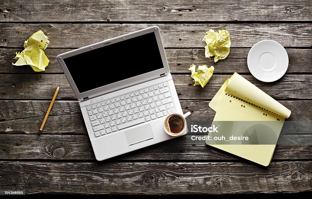 Laptop with cup of coffee. Top view. Top view of a laptop with coffee, blank notepad and pencil with sheets of crumpled paper on old wooden table. Blank Stock Photo