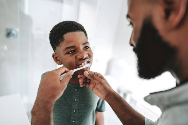 istock Father teaching son to brush teeth 1542688776