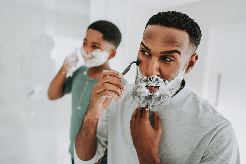 Father teaching son to shave his beard