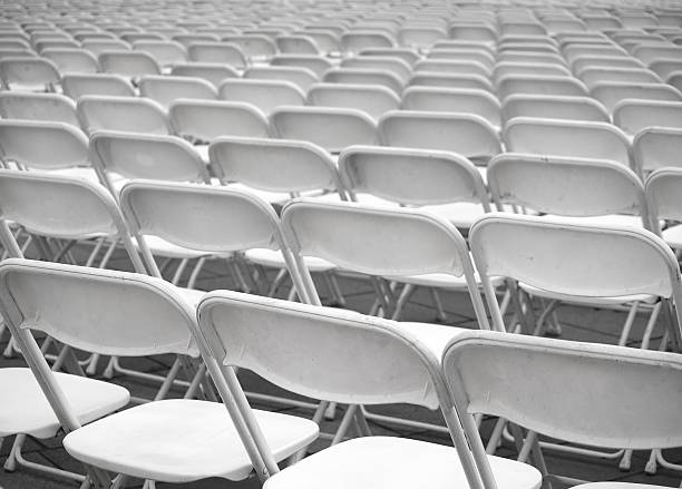 Sea of White Plastic Chairs Rows of plastic chairs are set up for an outdoor  performance.. folding chair stock pictures, royalty-free photos & images