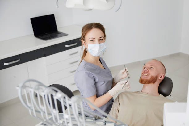 portrait of young female dentist standing by mid adult man in clinic. female dentist repairing patient tooth in dental ambulant - ambulant patient imagens e fotografias de stock