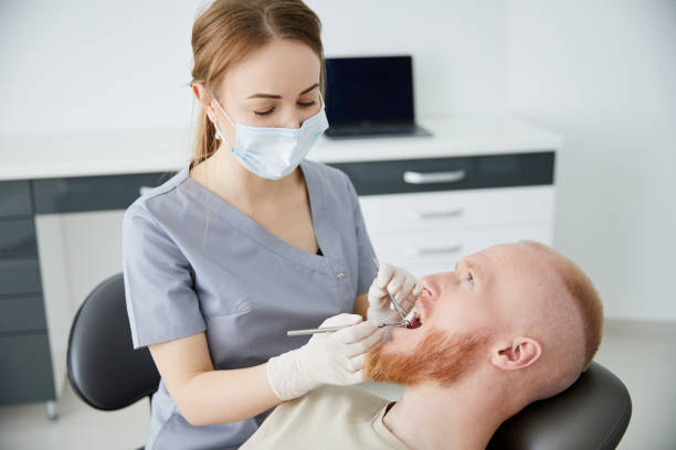 Portrait of young female dentist standing by mid adult man in clinic. Female dentist repairing patient tooth in dental ambulant Portrait of young female dentist standing by mid adult man in clinic ambulant patient stock pictures, royalty-free photos & images