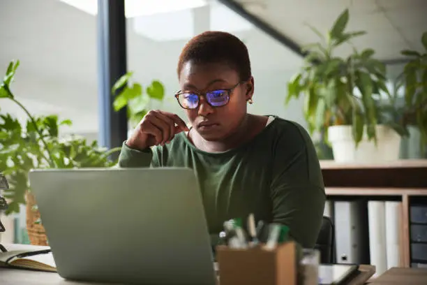 Photo of Thinking, research and business woman reading, article review and editing or news analysis in office. Focus, glasses reflection and African person, editor or journalist for online report on computer